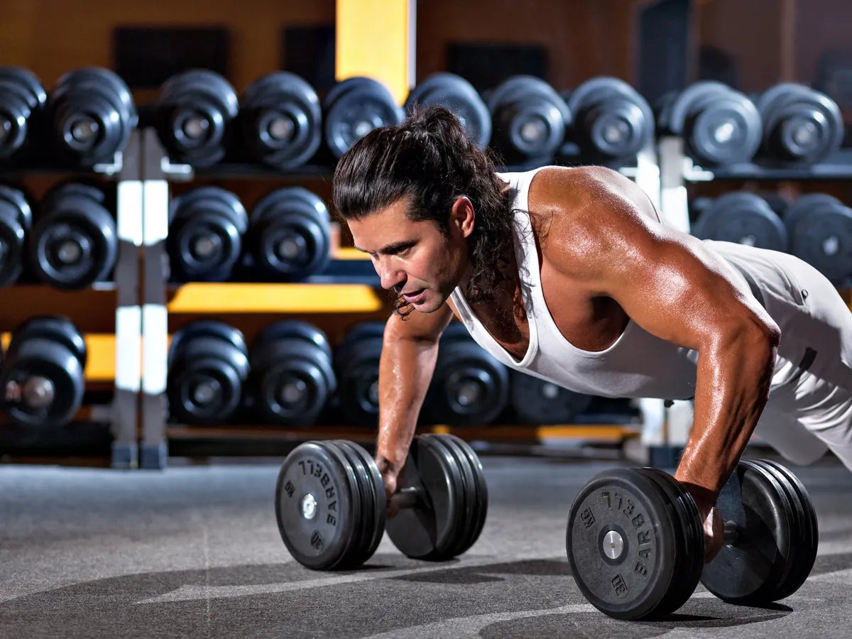 In the heart of a bustling gym, a determined athlete engages in an intense workout session, showcasing strength and focus. The scene captures the essence of dedication as the weights challenge his limits, inspiring others to push through their own barriers toward fitness goals.