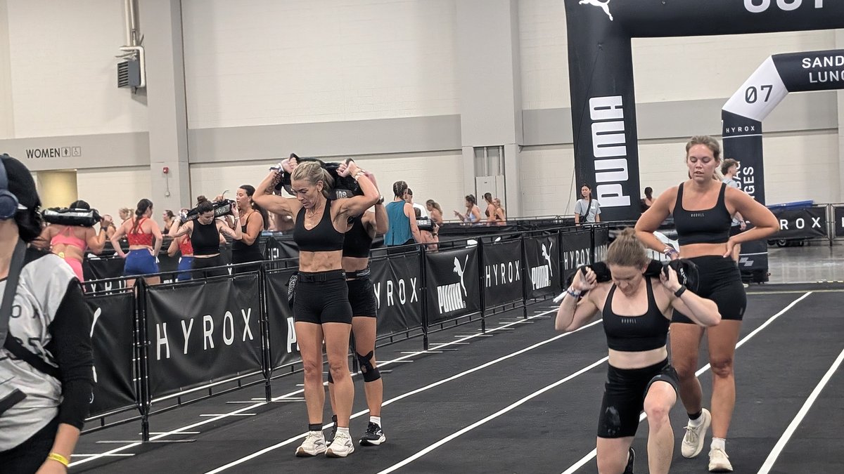 Competitors shouldering sandbags at the HYROX sandbag lunges station in Salt Lake City