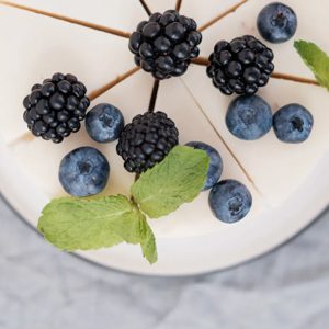 delicious creamy cheesecake with blueberries and blackberries. view from above. grey background. minimalism