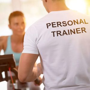 In a vibrant fitness studio, a dedicated personal trainer motivates a client on a stationary bike, embodying the spirit of personal wellness and empowerment. Their shared focus on fitness underlines the importance of guidance in achieving health goals.